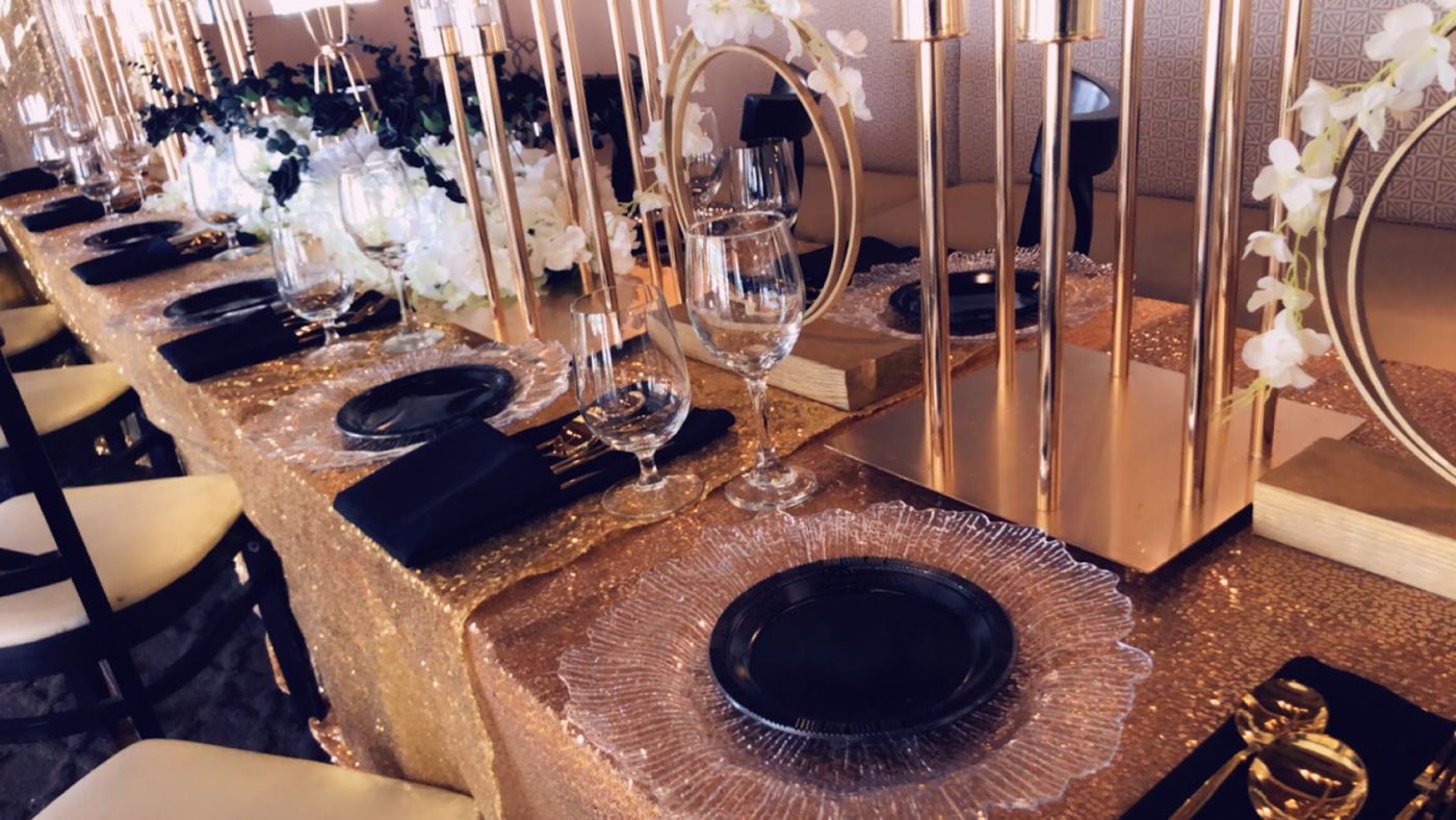 Mesa larga con platos dorados y servilletas negras